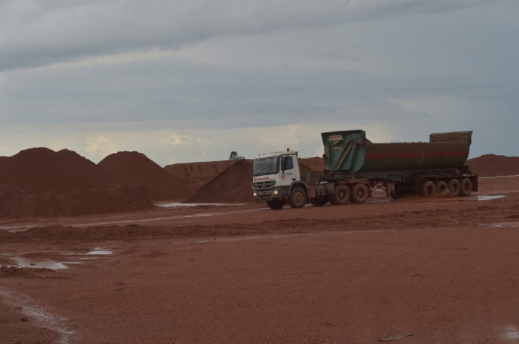 This picture taken in Kendawangan, West Kalimantan, on February 13, 2017 shows a truck carrying material next to piles of bauxite at a bauxite mine belonging to the Harita group.