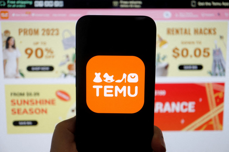 The logo of Temu, an e-commerce platform owned by PDD Holdings, is seen on a mobile phone displayed in front of its website, in this illustration picture from April 26, 2023.