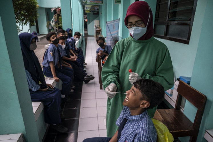 A health worker conducts an antigen test for COVID-19 for students on June 9, 2022, at a junior high school in Surabaya, East Java.
