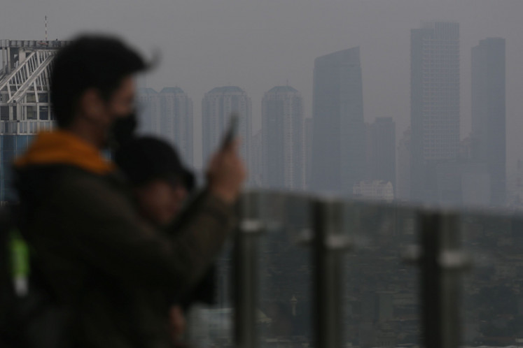 People take pictures of Jakarta from a high-riser with the hazy sky in the background due to air pollution on June 6, 2023. The capital’s AQI score of 157 is 13.4 times higher than the level the World Health Organization (WHO) considers safe.