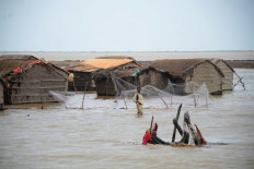 A man wades through water in Pakistan's Sindh province on June 15, 2023, as howling gales and crashing waves pound the coastline of India and Pakistan in the hours counting down to the landfall of cyclone Biparjoy, which prompted mass evacuations.