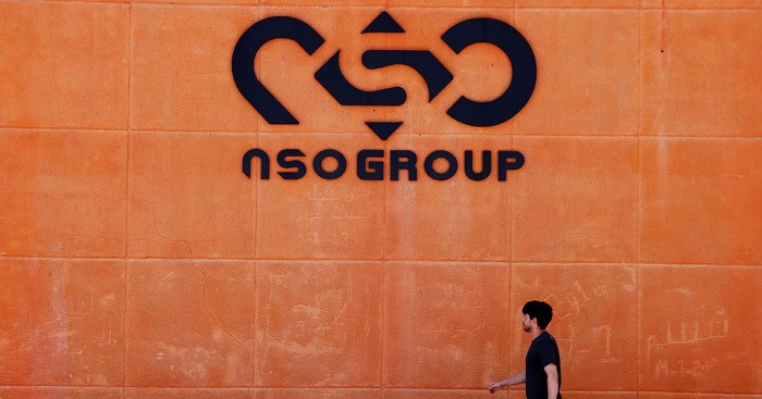 A man walks past a logo of the NSO Group, producer of Pegasus spyware.