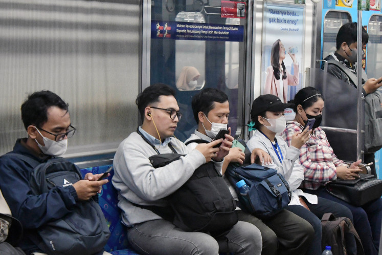 Passengers use their gadgets on board a commuter line train at Bekasi Station, West Java, on June 12, 2023. The Transportation Ministry has issued a circular allowing healthy train passengers to travel without face masks while recommending that people still get COVID-19 vaccines.