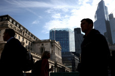People walk outside the Bank of England in the City of London financial district of London on May 11, 2023.