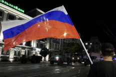 A man waves the Russian national flag as the members of Wagner group prepare to pull out from the headquarters of the Southern Military District to return to their base in Rostov-on-Don late on June 24, 2023. 
