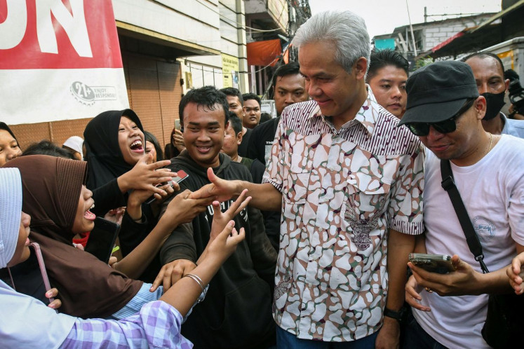 Indonesian Democratic Party of Struggle (PDI-P) presidential nominee Ganjar Pranowo (center) shakes hands with supporters as he visits a low-income residential area in Pademangan, North Jakarta, on June 25, 2023.