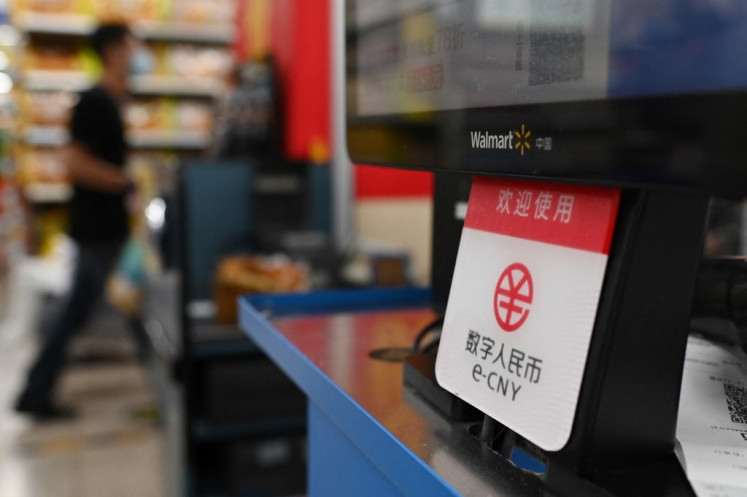 A sign indicating payment is accepted using China's new digital currency is displayed at a checkout in a Walmart store in Beijing on July 2, 2021.