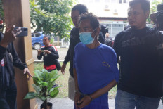 Police officers flank a sexual abuse and murder suspect (center) at the Banyumas Police headquarters in Central Java on June 27, 2023.