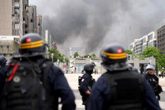 CRS riot police face protesters, with the “Grande Arche de la Defense“ seen in the background, at the end of a commemoration march for a teenage driver shot dead by a policeman, in the Parisian suburb of Nanterre, on June 29, 2023. 