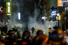 Demonstrators run as French police officers use tear gas in Paris on July 2, 2023, five days after a 17-year-old man was killed by police in Nanterre, a western suburb of Paris. French police arrested 1311 people nationwide during a fourth consecutive night of rioting over the killing of a teenager by police, the interior ministry said on July 1, 2023. France had deployed 45,000 officers overnight backed by light armoured vehicles and crack police units to quell the violence over the death of 17-year-old Nahel, killed during a traffic stop in a Paris suburb on June 27, 2023.
