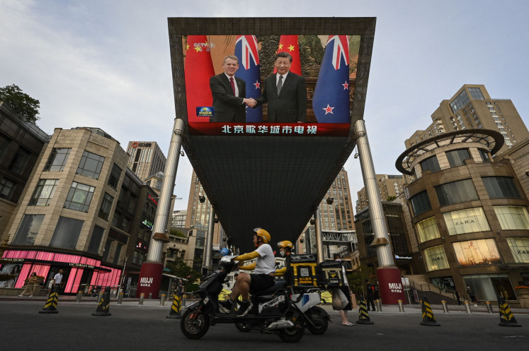 An outdoor screen shows news coverage of then New Zealand's prime minister Chris Hipkins meeting with China's President Xi Jinping at the Great Hall of the People, along a street in Beijing on June 27, 2023.