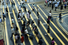 People cross a road in Central, a financial hub in Hong Kong, China, on July 3, 2023.
