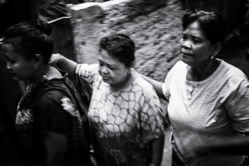 Musriyah (center) walks with her daughters Tyas (left) and Yati (right).