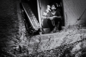 Yati sits in front of her house.
