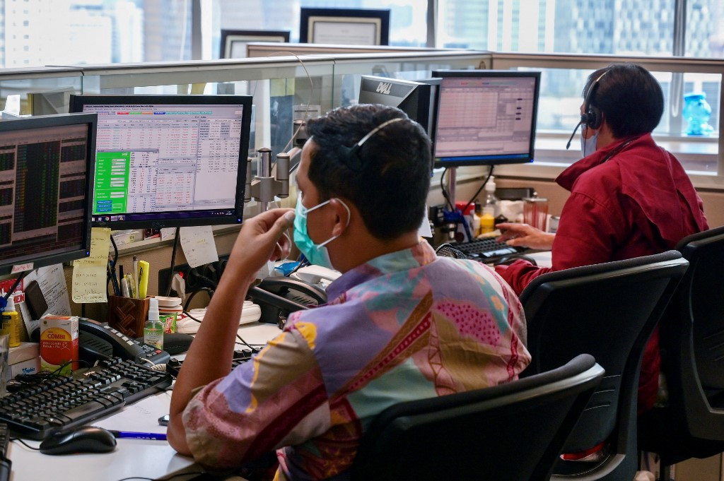 Traders look at their screens while monitoring stock movements in Jakarta on March 16, 2023.