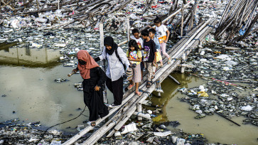 Coastal children enthusiastically walk on a bamboo bridge on their way to learn new things that have not been taught in their schools.