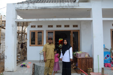 Ike Ernawati (right), Arsi Najilah Madani (center) and Nurul Hakim (left) in front of their house.
