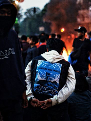 A young man wearing a jacket with the words "KAMI BERSAMA WARGA TAMANSARI" (“We are with the people of Tamansari”) showing support for the victims of the evictions in Tamansari.