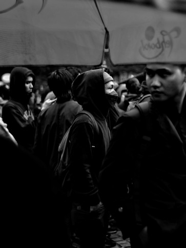 A young man walking alone in a crowd of people.