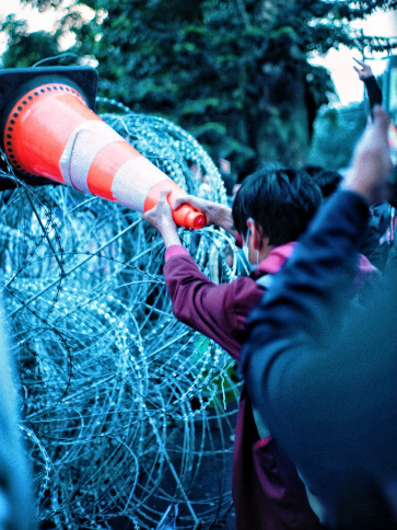 A college student tries to remove wire with a traffic cone.