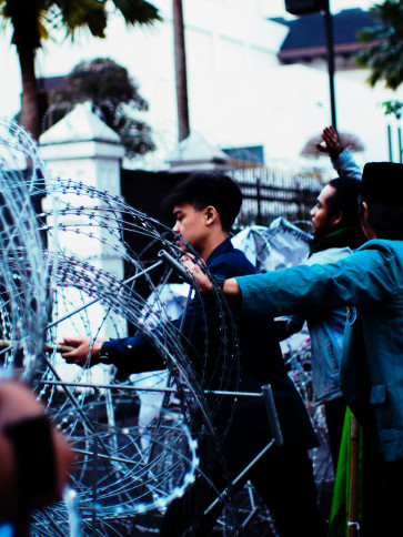 A student tries to remove wire blocking the entrance to the Bandung DPRD building.