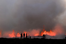People watch flowing lava during an volcanic eruption near Litli Hrutur, south-west of Reykjavik in Iceland on July 10, 2023.