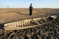 An Iraqi man looks at a grounded boat along a dried-up bank in the Chibayish marshes in Iraq's southern Dhi Qar province on June 25, 2023.