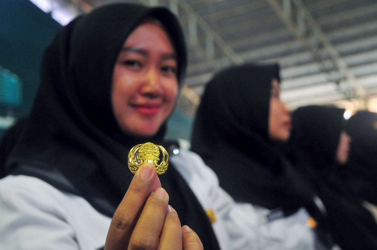 It’s official: A teacher shows her Civil Servants Corps badge during an appointment ceremony in Kudus, Central Java, on July 11, 2023. Kudus regental administration inducted 407 teachers as civil servants during the event. Antara/Yusuf Nugroho
