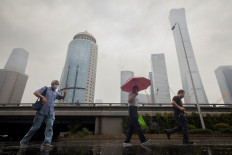 People walk in the Central Business District on a rainy day in Beijing, China, on July 12, 2023.