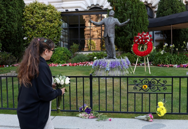 A mourner drops flowers near a statue of Tony Bennett at the Fairmont Hotel on July 21, 2023 in San Francisco, California.