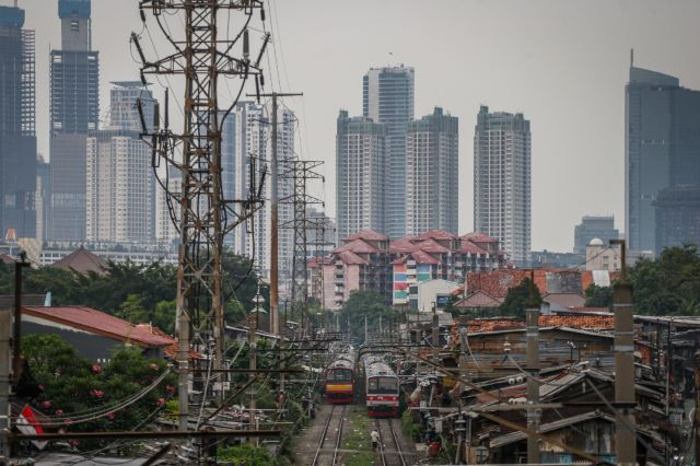 City landmarks: A Commuter Line train speeds through a low-income residential area, as high-rise buildings, including those belonging to national banks, stand out in Jakarta on June 27, 2023.