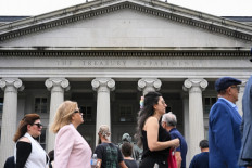 People pass by the Treasury Building on Pennsylvania Avenue in Washington, DC, on May 19, 2023.