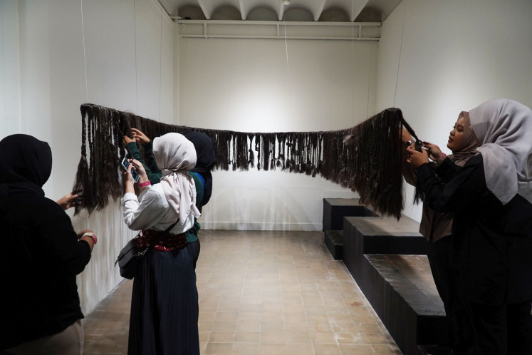 Tactile piece: Visitors interact with a work titled Things left unsaid on the edge of her fingers by Surya Amalia, which is made of synthetic hair and rubber bands.