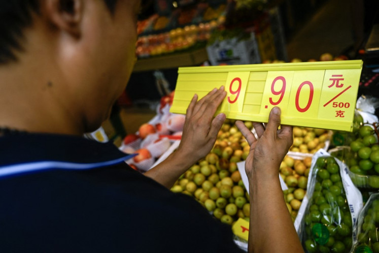A fruit and vegetable vendor updates the price of an item on August 9, 2023, at a market in Beijing.