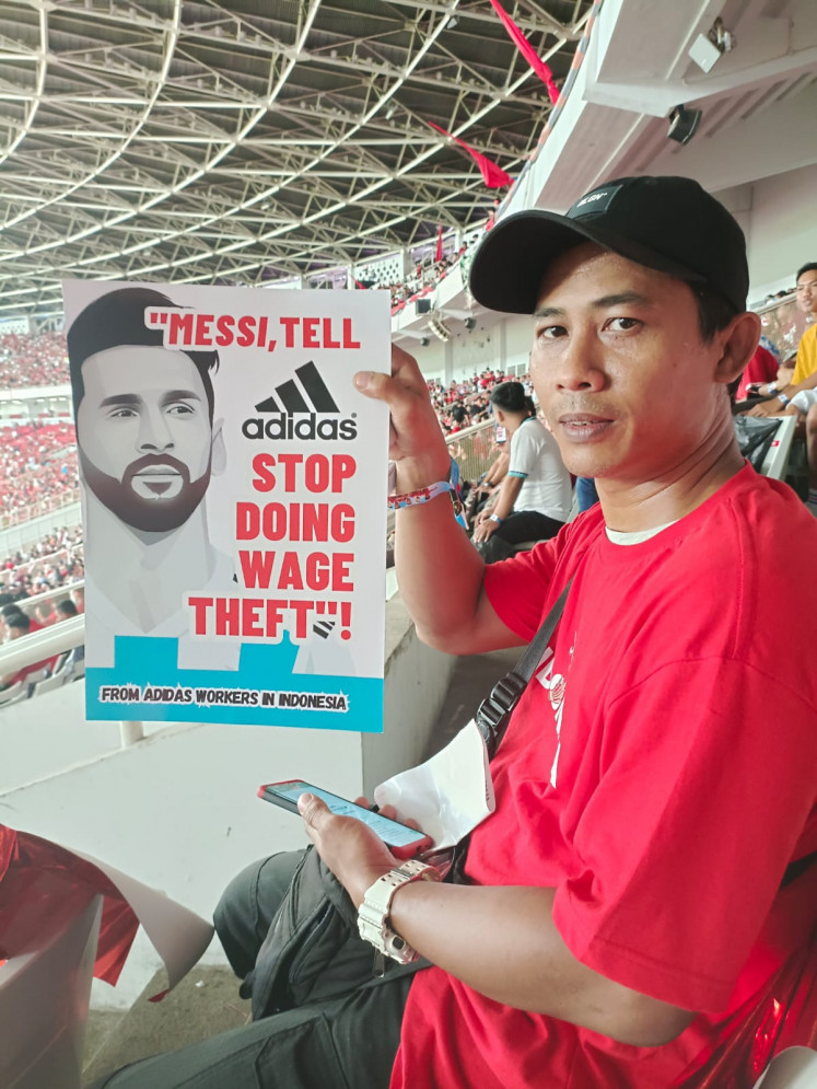 A worker employed by Panarub Indonesia, a local contractor of global apparel maker Adidas, holds a protest poster in a soccer stadium on June 19, 2023. Workers have expressed dissatisfaction with working conditions and say they are not getting enough time to rest.