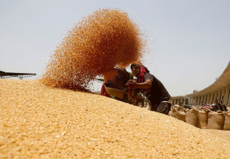 A worker sifts wheat before filling sacks on May 16, 2022, in the market yard of the Agriculture Product Marketing Committee (APMC) on the outskirts of Ahmedabad, India.