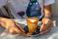 A woman holds a glass of milk coffee in Bali in this undated stock photo.
