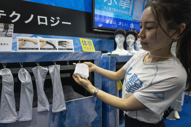 A staff member displays cooling arm sleeves made with special fabric by Freeze Tech, during the Tokyo Extreme Heat Countermeasures Exhibition during Techno Frontier 2023 at the Tokyo Big Sight venue in Tokyo on July 27, 2023.
