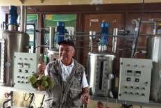 Biofuel researcher Dibyo Pranowo stands in front of the prototype of a biodiesel reactor he invented as he shows drupes (left) and kernels of ‘kemiri sunan’ (Sunan candlenut) on Jan. 16, 2019, at the Agriculture Ministry’s research center in Sukabumi, West Java.