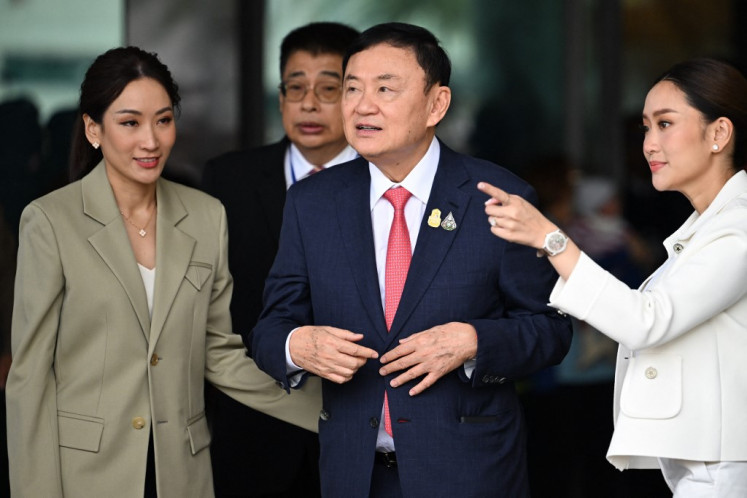 Former Thai Prime Minister Thaksin Shinawatra greets his supporters next to his daughters Paetongtarn Shinawatra (Second right) and Pintongtha Kunakornwong (left) after landing at Bangkok's Don Mueang airport on August 22, 2023. 