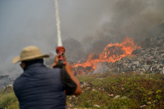 A firefighter tries to extinguish a fire on Aug. 23, 2023, at the Sarimukti landfill in West Bandung regency, West Java.