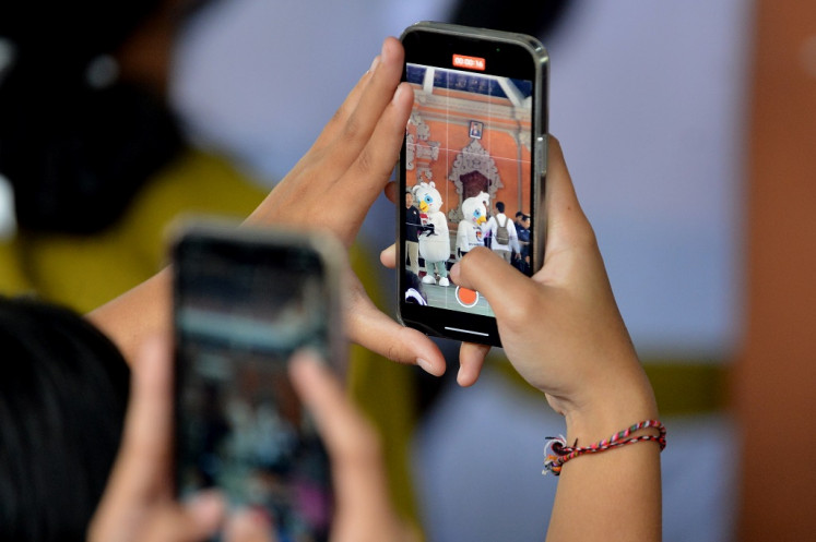 A student records the performance of the 2024 general election mascots, Sura and Sulu, using her mobile phone on Aug. 14, 2023, during an event held by Badung regency General Elections Commission (KPU) in Badung, Bali. The commission is wooing first-time voters to in the upcoming election.