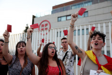 Protesters hold red cards as they protest against President of the Royal Spanish Football Federation, Luis Rubiales,  outside the federation headquarters in Las Rozas de Madrid, Spain on Aug. 25, 2023.