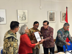 Law and Human Rights Minister Yasonna Laoly (second right) hands over a framed image of a free visa to Indonesian political exile Sri 'Ning' Budiarti (second left) while senior minister Mahfud MD (center) looks on, during an event at the De Schakel building in Amsterdam, the Netherlands, on Sunday, Aug. 27, 2023. The government is meeting with the exile community overseas as part of its push to settle past rights atrocities using nonjudicial means.