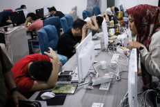 This picture taken on August 29, 2023 shows a police officer looking at a group of Chinese nationals who were arrested during a police raid on suspicion of running an online love scam syndicate that ensnared hundreds of victims in China, at a building of the Kara Industrial Park in Batam, in Riau Islands province. 