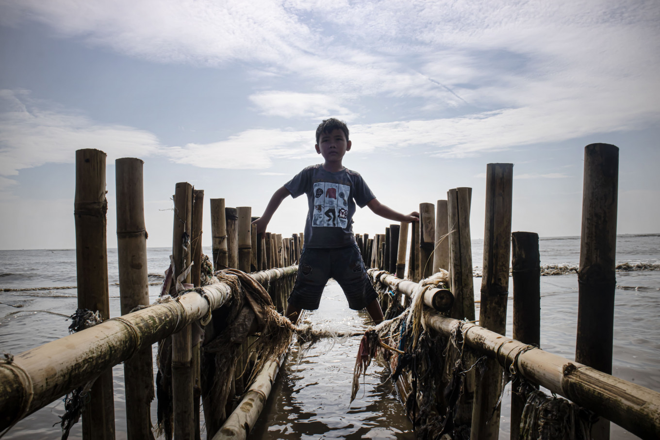 A boy plays on a sea wave breaker made from bamboo in Cemarajaya village in Karawang, West Java. 