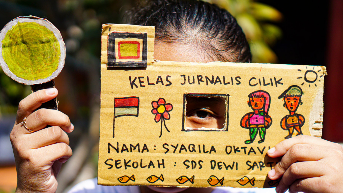 A girl pretends to take a photo with a cardboard camera, one of tools created in Kelas Jurnalis Cilik to help provoke children’s imaginations on the dynamics of their environment.