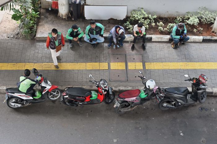 Drivers of on-demand transportation services Gojek and Grab wait for passengers on June 24, 2020 in Jakarta. The gig economy has contributed at least US$7 billion to the Indonesian economy and jobs for at least 4 million people, but falls short in offering decent work.