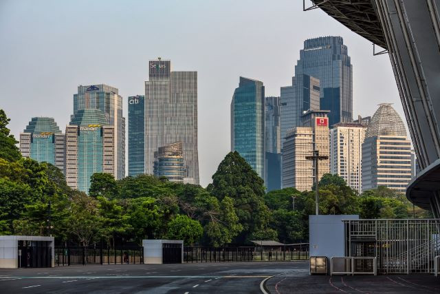 High-rise office buildings belonging to banking institutions, including the Menara Mandiri twin towers (left), loom above the verdant perimeter of the Gelora Bung Karno sports complex along Jl. Sudirman in South Jakarta as the sun begins to set on Aug. 27, 2021.
