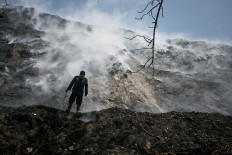 A firefighter checks a fire that continues to burn a mountain of trash at Putri Cempo landfill in Surakarta, Central Java, on Sept. 19, 2023. The National Disaster Mitigation Agency (BNPB) has deployed helicopters to conduct waterbombing to help put out the fire.